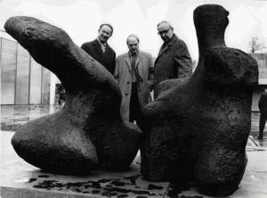 Das Schwarz-Weiß-Foto zeigt den Künstler Henry Moore zwischen Oberbürgermeister August Seeling (links) und Museumsdirektor Gerhard Händler am 25. März 1965 auf dem Skulpturenhof des Lehmbruck Museums. Sie stehen hinter der Skulptur "Two Piece Reclining Figure No. 1", die Henry Moore 1959 schuf.